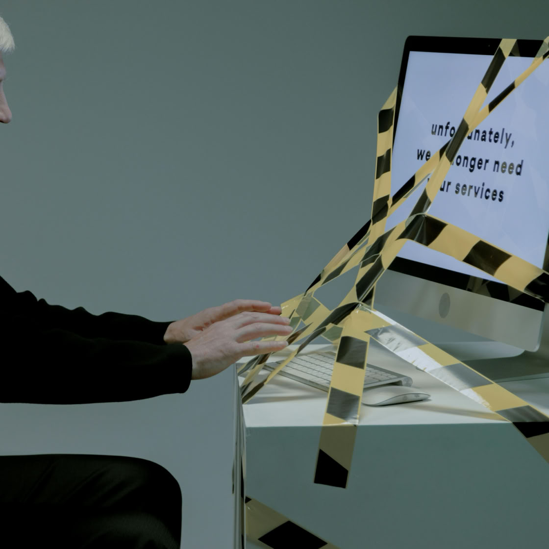 Elderly man at computer with termination notice, facing unemployment.