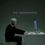 Elderly man using computer with 'no vacancies' displayed, highlighting job search struggles.